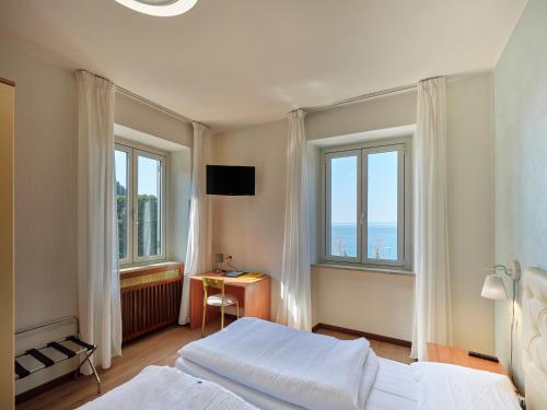 a hotel room with two beds and two windows at Hotel San Marco in Garda