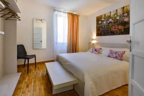 a bedroom with a white bed with a painting on the wall at Ma Choupette in Torre Pellice