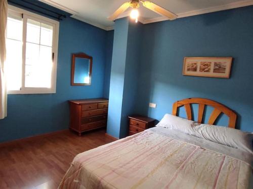 Schlafzimmer mit blauen Wänden, einem Bett und einem Fenster in der Unterkunft Apartamento con bike station para 4 pax. in Puente de Génave