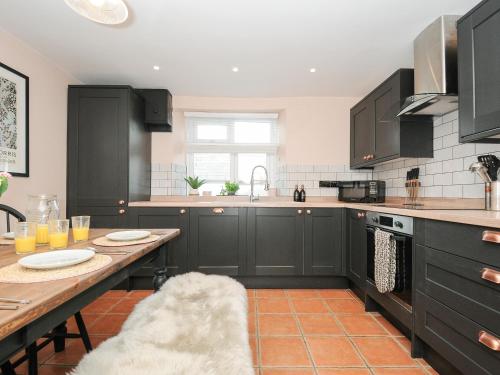 a kitchen with black cabinets and a wooden table at Skylarks in Looe