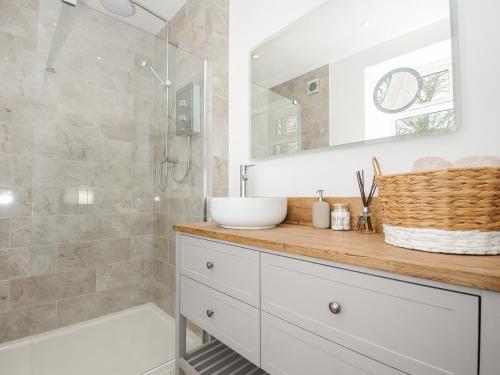 een badkamer met een witte wastafel en een douche bij Skylarks in Looe