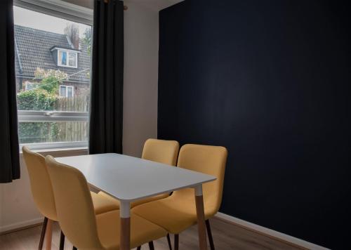 a dining room with a white table and yellow chairs at Cottenham - City Centre with Free Private Parking 2 toilets 4 Bedroom Sleeps 8 in Newcastle upon Tyne