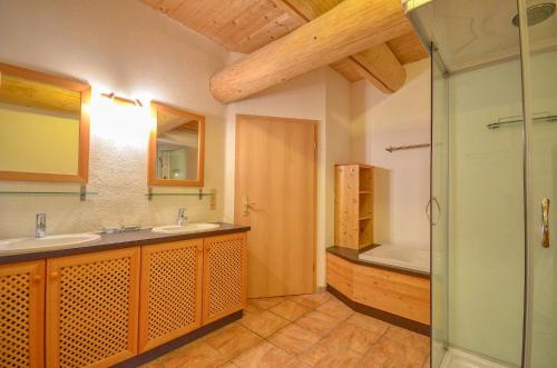 a bathroom with two sinks and a shower and a tub at Chalet Stabler - by Alpen Apartments in Zell am See