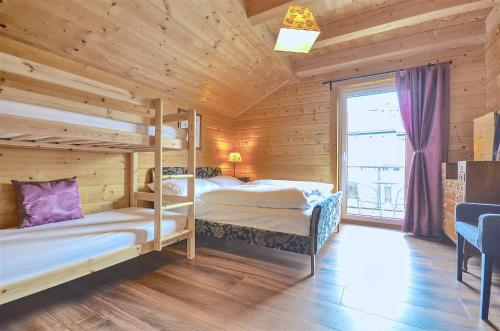 two bunk beds in a wooden room with a window at Chalet Seven - by Alpen Apartments in Zell am See