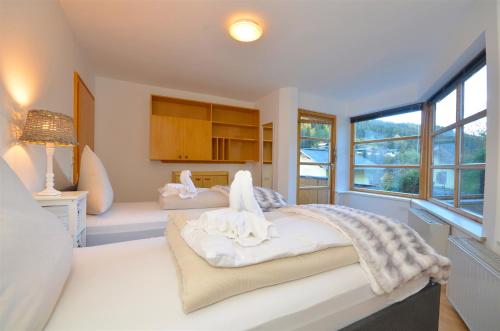 a bedroom with two beds with white sheets and a window at Haus Thumersbach - by Alpen Apartments in Zell am See