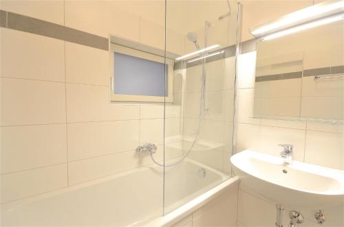 łazienka z prysznicem, umywalką i wanną w obiekcie Mozart Top 2 - by Alpen Apartments w mieście Zell am See