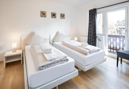 2 łóżka w białym pokoju z oknem w obiekcie Mozart Top 2 - by Alpen Apartments w mieście Zell am See