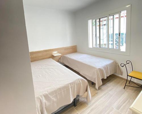 2 camas en una habitación con ventana en CA LA LOLA, en Banyeres del Penedés