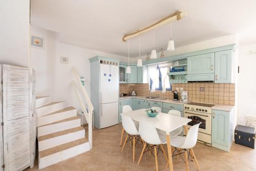 a kitchen with blue cabinets and a table and chairs at Wonderful maisonette overlooking the Aegean Sea in Petriaí