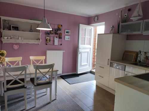 eine Küche mit lilafarbenen Wänden sowie einem Tisch und Stühlen in der Unterkunft Pier 12 Ferienwohnung in Eckernförde