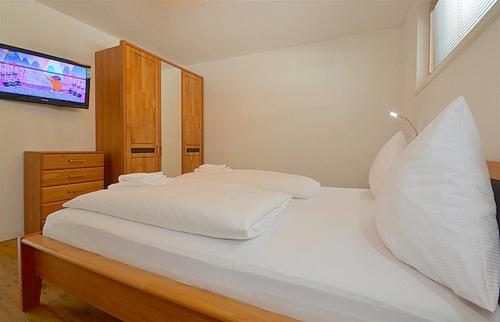 a bedroom with a white bed with a tv on it at Sonnenhaus A - by Alpen Apartments in Zell am See