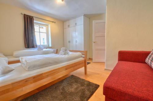 1 dormitorio con 2 camas y sofá rojo en Villa Skilift-Seeblick - by Alpen Apartments, en Zell am See