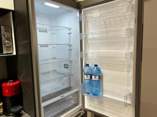 zwei Flaschen Wasser in einem leeren Kühlschrank in der Unterkunft 2A-Precioso Apartamento en pleno centro. A estreno in Alcázar de San Juan