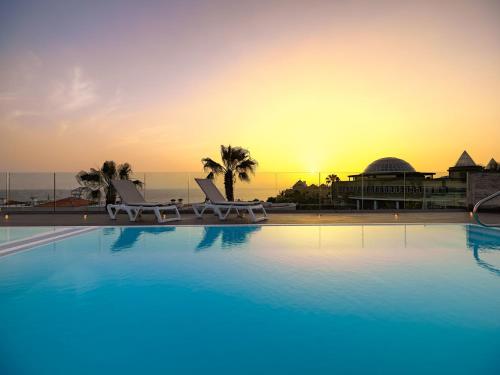 a swimming pool with a sunset in the background at Adrián Hoteles Colón Guanahaní Adultos Only in Adeje