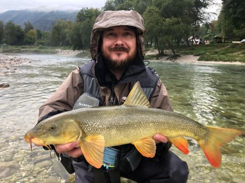 a man holding a large fish in a river at Guesthouse Pri Štefanu in Most na Soči