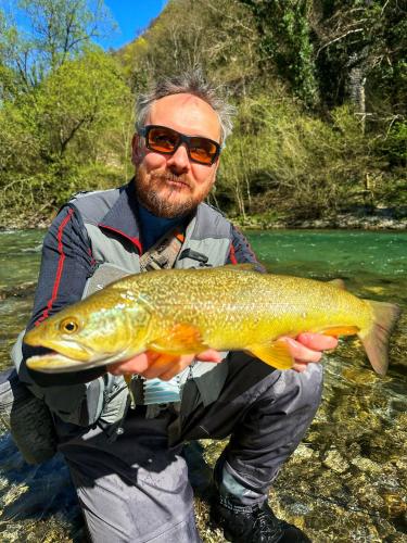 a man holding a fish in a river at Guesthouse Pri Štefanu in Most na Soči