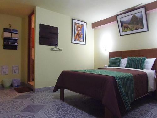 a bedroom with a bed and a tv on the wall at Hostal Pablo's House in Machu Picchu