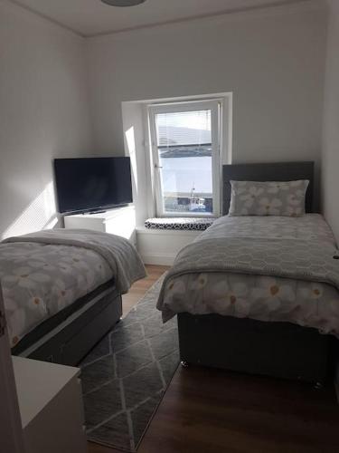 1 dormitorio con 2 camas y ventana en Wee Harbour View en Millport