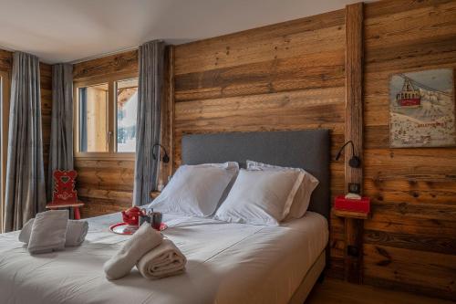 - une chambre avec un grand lit et des murs en bois dans l'établissement Chalet Folie Douce, aux Gets