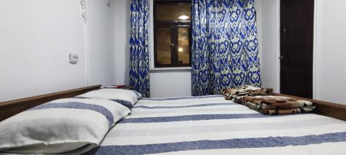 a bedroom with two beds with blue and white curtains at Diyor Guest house in Bukhara