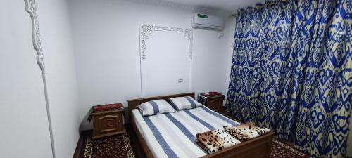 a bedroom with a bed and a blue and white curtain at Diyor Hostel in Bukhara