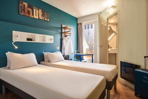 two beds in a room with blue walls at ibis budget Saint-Ouen-l'Aumône in Saint-Ouen-lʼAumône