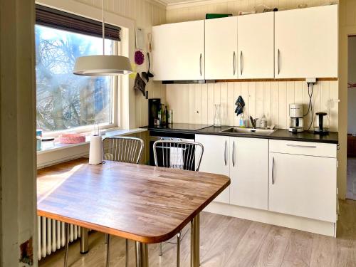 Liv's Guesthouse في تورشافن: مطبخ بدولاب بيضاء وطاولة خشبية