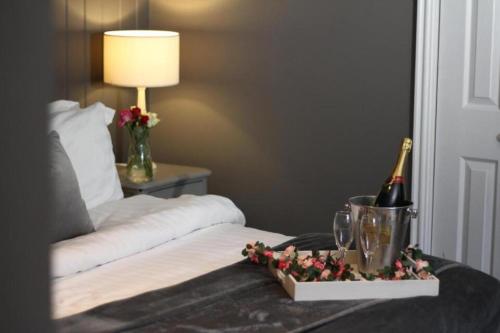 a bed with a bottle of wine on a table at The Old Talbot Hotel Milton Keynes in Potterspury