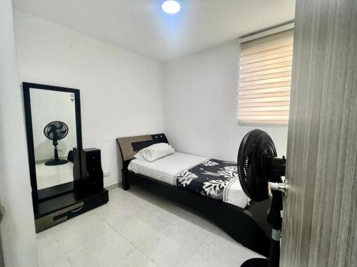 Dormitorio pequeño con cama y espejo en Apartamento en Cartagena Cerca a la Playa, en Cartagena de Indias