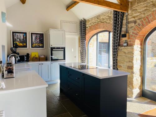 una cocina con armarios blancos y una isla negra en Contemporary Luxury Barn Conversion in County Durham, en Durham