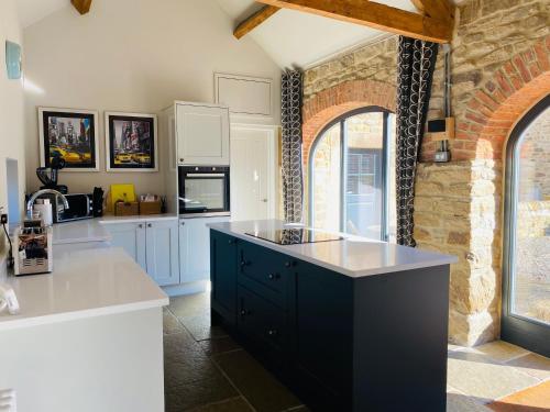 a kitchen with white cabinets and a black island at Contemporary Luxury Barn Conversion in County Durham in Durham