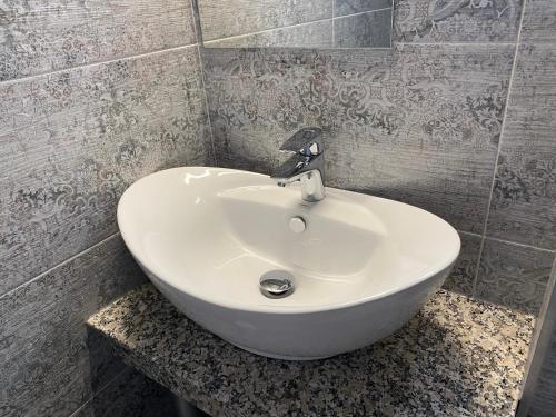 a white sink in a bathroom with a tiled wall at Pensiunea Korona in Miercurea-Ciuc