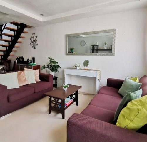 ein Wohnzimmer mit zwei lila Sofas und einem Tisch in der Unterkunft 2BR 2BT home with pool between Tagbilaran and Panglao in Dauis