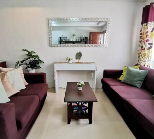 道伊斯的住宿－2BR 2BT home with pool between Tagbilaran and Panglao，客厅配有两张紫色沙发和一张桌子