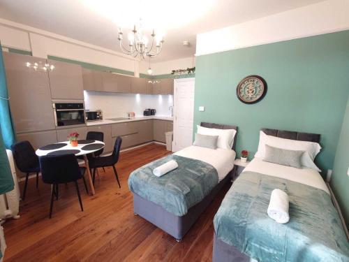 a bedroom with two beds and a table and a kitchen at Kings Cross Apartment in London