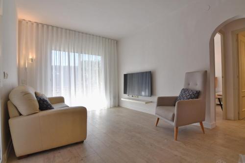 ein Wohnzimmer mit einer Couch und einem Sessel und einem Fernseher in der Unterkunft Apartament Luna in L'Escala