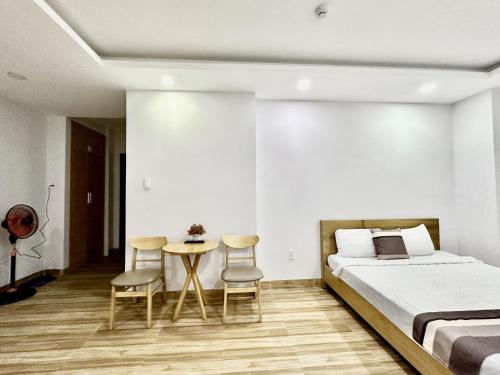 a bedroom with a bed and a table and chairs at The Jade Hotel near Tan Son Nhat Airport in Ho Chi Minh City