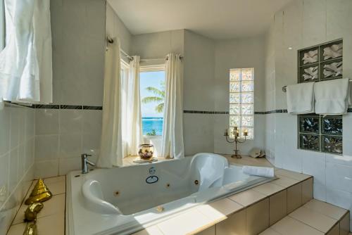 a white bathroom with a tub and a window at Private Beach Ocean Front Boat Dock Tiki Bar in Savaneta