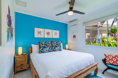 a blue bedroom with a bed and a window at GolfCourse Tropical Guest House Private Pool in Tierra del Sol in Palm-Eagle Beach