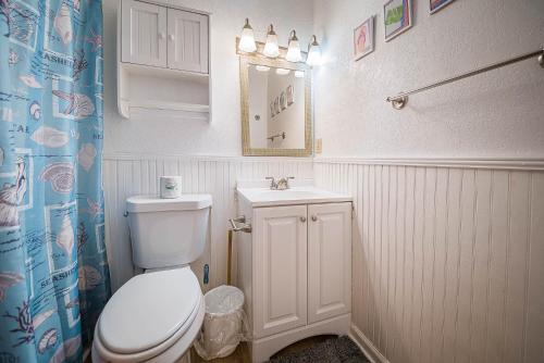 La salle de bains est pourvue de toilettes blanches et d'un lavabo. dans l'établissement Escape to Paradise, à Kitty Hawk
