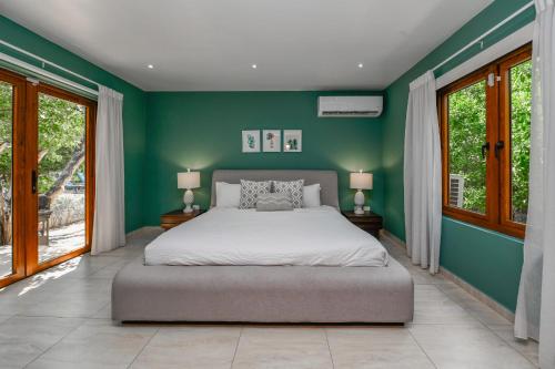 a bedroom with a bed with green walls and windows at Villa Adelaida in Palm-Eagle Beach