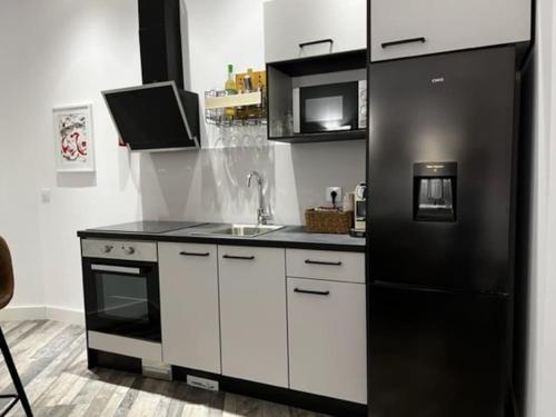 a kitchen with a black refrigerator and a sink at 1B-Precioso Apartamento en pleno centro. A estreno in Alcazar de San Juan