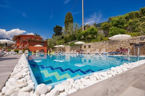 una gran piscina con sillas y sombrillas en Beach Hotel Rosa, en Malcesine