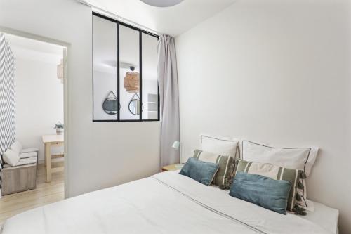 une chambre avec un lit blanc avec des oreillers bleus dans l'établissement Cozy 2-bedroom near Montmartre, à Paris