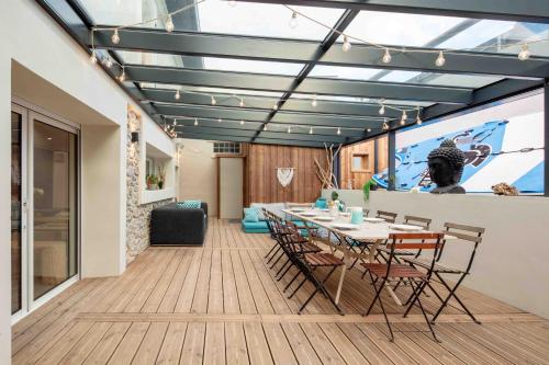 una sala da pranzo con tavolo, sedie e schermo di Ted Surf House a Capbreton