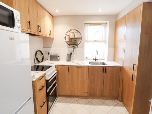 a kitchen with wooden cabinets and a sink at The Flat in Carlisle