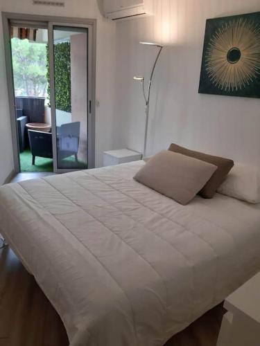 Cette chambre comprend un grand lit blanc et une table. dans l'établissement Farniente Riviera, à Mandelieu-la-Napoule