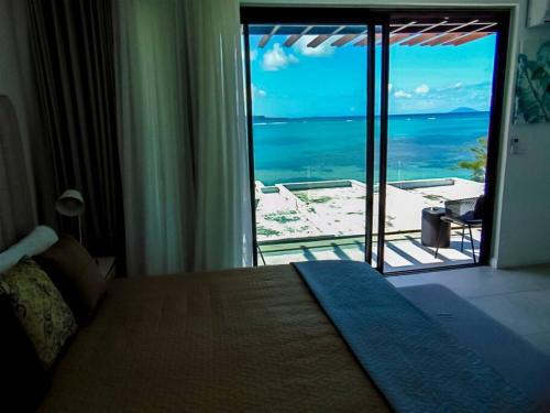 1 dormitorio con cama y vistas al océano en O Kouche Soley - Duplex Pied Dans L'eau, en Cap Malheureux