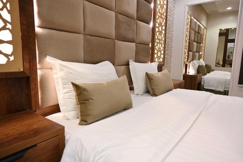 ليوان الخليج للوحدات السكنية المفروشة في الرياض: غرفة نوم بسرير كبير عليها شراشف ووسائد بيضاء