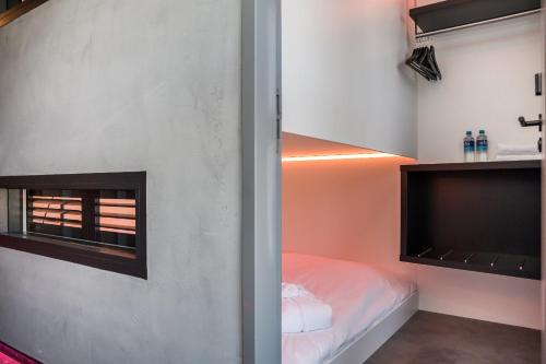 a small bedroom with a bed and a tv at THIS HO(S)TEL in Amsterdam